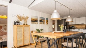 Et moderne køkken med træskabe, en central ø og hængende lamper.