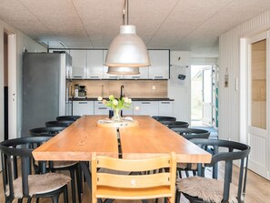 A modern kitchen with a central island, black chairs, and a hanging light fixture. - 8 Person Holiday Home in Hvide Sande (Hvide Sande)