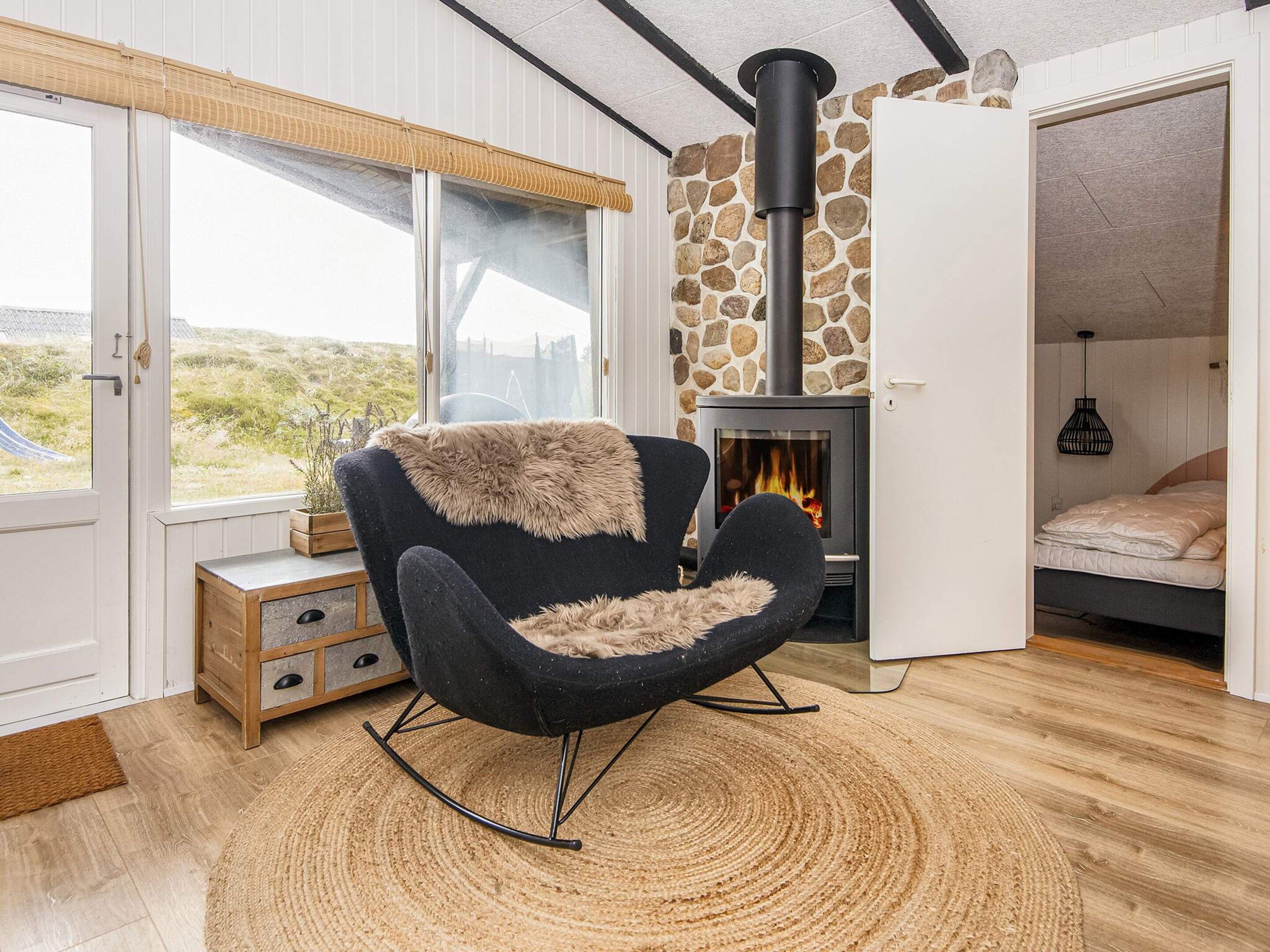 Una habitación acogedora con chimenea de piedra, una mecedora y una cama.