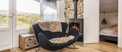 Una habitación acogedora con chimenea de piedra, una mecedora y una cama.