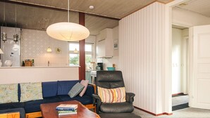 A living room with a sofa, a chair, a coffee table, and a hanging light fixture.