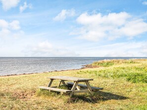 A picnic table on a grassy area near a body of water.