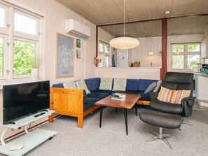 Un salon avec un téléviseur, un canapé, une table basse et un fauteuil.