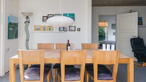 A dining area with a wooden table and chairs, a hanging light fixture, and framed pictures on the wall.