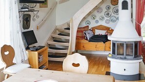 Ein gemütliches Interieur mit einer Holztreppe, einem Bett mit Karo-Bettwäsche, einem weißen Herd und einem an der Wand montierten Fernseher.