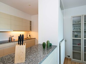 A kitchen with a granite countertop, a wooden cutting board, and a cabinet with kitchen utensils. - 5 Star Holiday Home in Ebeltoft (Ebeltoft)