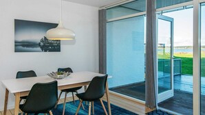 A modern dining area with a white table, black chairs, a blue rug, and a pendant light. - 5 Star Holiday Home in Ebeltoft (Ebeltoft)