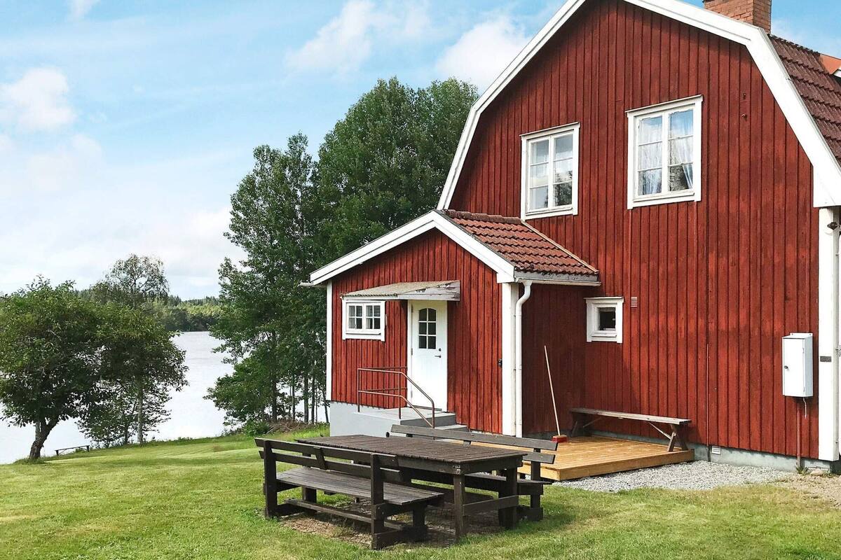 Una casa de madera roja con un pequeño balcón y una mesa de picnic.