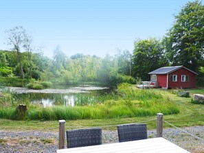 A lakeside cabin with a dining area and a small deck overlooking the water. - 4 Person Holiday Home in Smedstorp (Smedstorp)