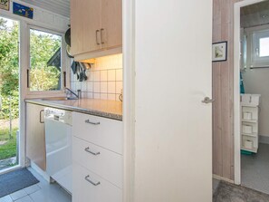 A compact kitchen with a sink, countertop, and wooden cabinets. - 8 Person Holiday Home in Knebel (Knebel)