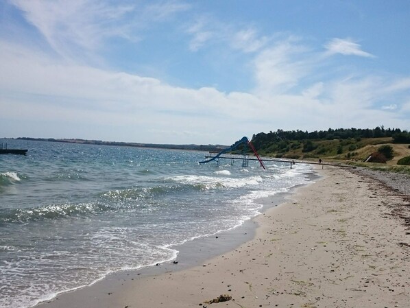 A beach with a water slide and a sandy shore.