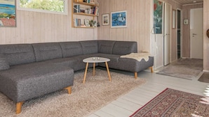 Ein modernes Wohnzimmer mit einem grauen Ecksofa, einem kleinen runden Tisch und einem Bücherregal.