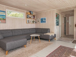 A modern living room with a grey sectional sofa, a small round table, and a bookshelf.