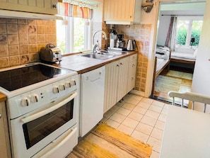 A compact kitchen with a stove, oven, sink, and a coffee maker.