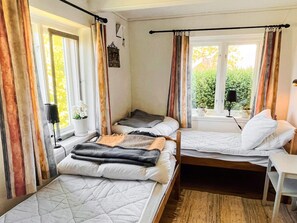 Una habitación con dos camas, un escritorio y una ventana con cortinas.
