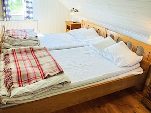 A double bed with a wooden headboard, a bedside table with a lamp, and a window with curtains. - 10 Person Holiday Home in Hammenhog (Hammenhög)