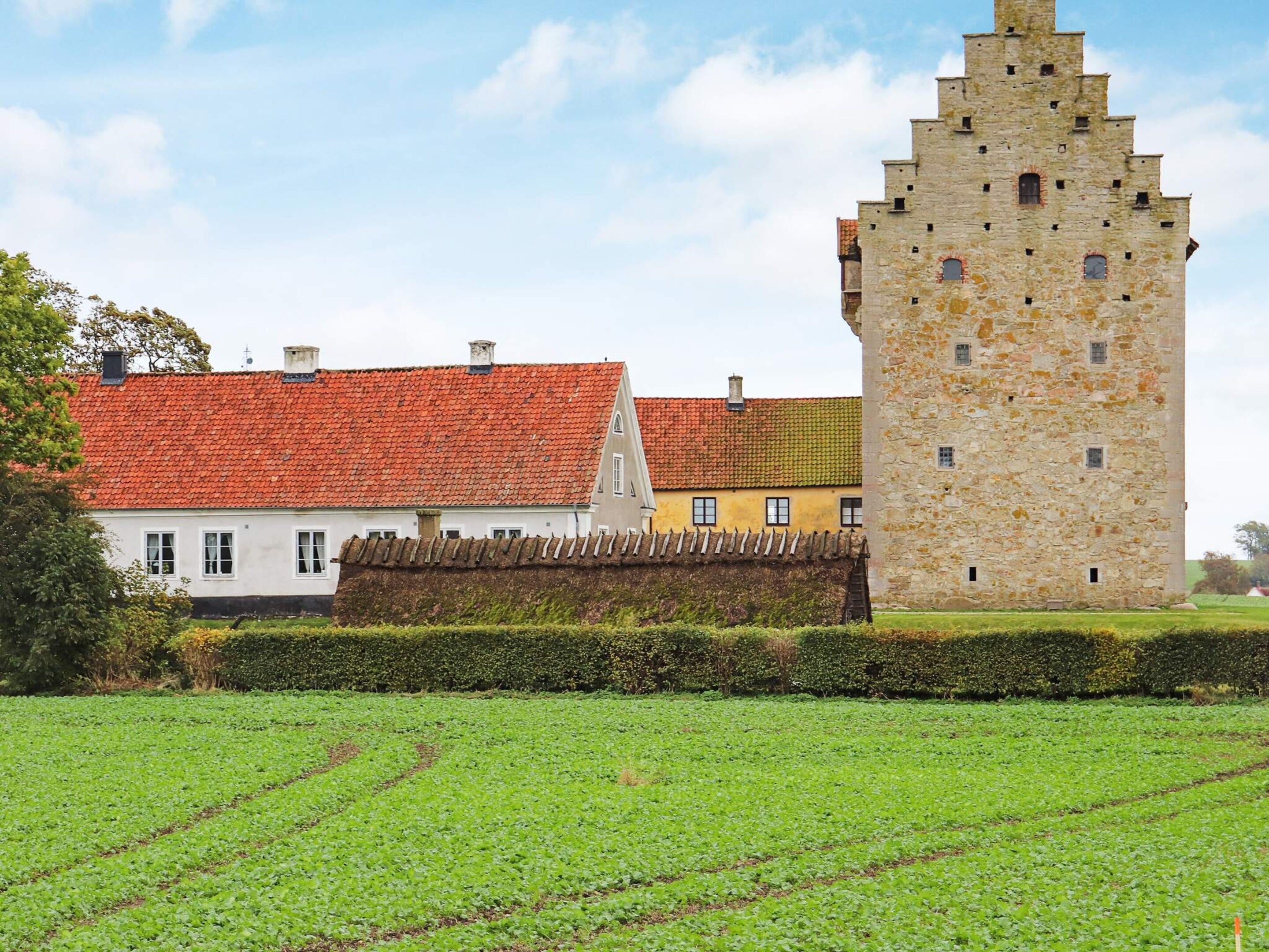A historic building with a stone tower and a red-tiled roof.