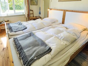 A double bed with a wooden headboard, a bedside table, and a window with curtains. - 10 Person Holiday Home in Hammenhog (Hammenhög)