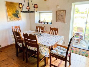 A dining area with a table, chairs, a chandelier, a window, and a door leading outside. - 10 Person Holiday Home in Hammenhog (Hammenhög)