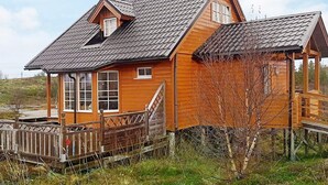 A wooden cabin with a gabled roof, a front porch, and a small deck. - Holiday Home in Austbø (Alstahaug)