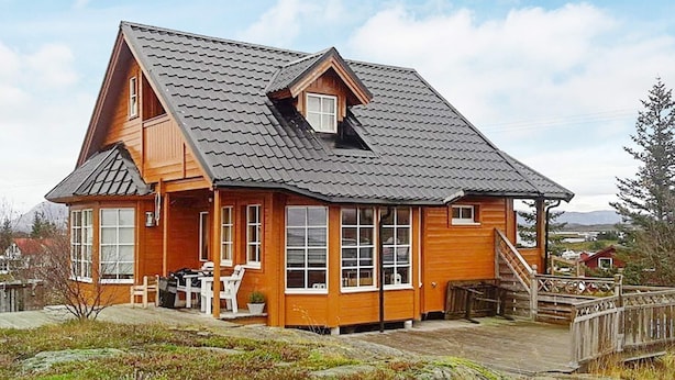 A wooden cabin with a steeply pitched roof, large windows, and a porch area. - Holiday Home in Austbø (Alstahaug)