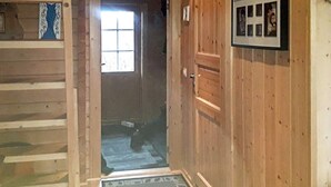 A wooden cabin interior with a door leading to a room, a window, and a framed photo on the wall. - Holiday Home in Austbø (Alstahaug)