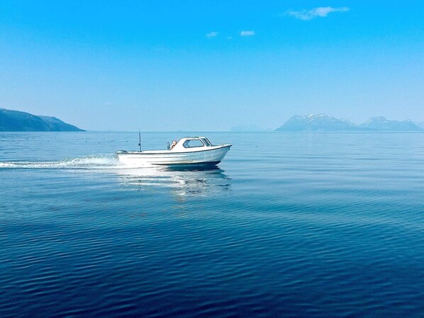 A boat on calm water with distant mountains.