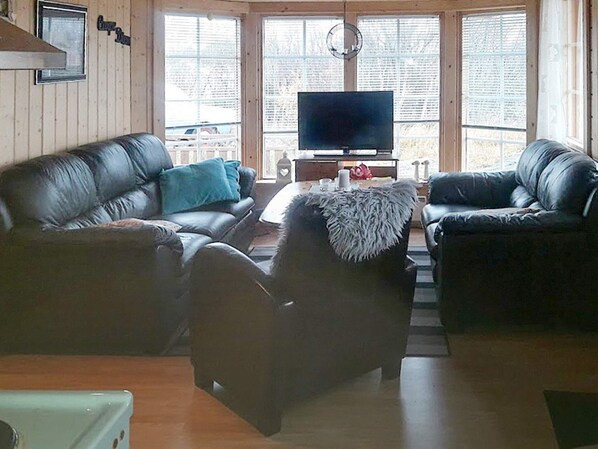 A living room with two leather sofas, a coffee table, and a television. - Holiday Home in Austbø (Alstahaug)