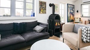 A cozy living room with a fireplace, a sofa, a chair, and artwork on the walls. - 8 Person Holiday Home in Frorup (Frørup)