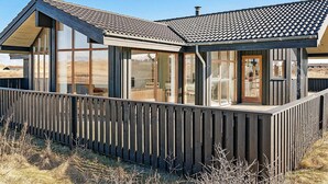 A wooden cabin with large windows, a deck, and a sloped roof. - 5 Star Holiday Home in Hjorring (Hjørring)