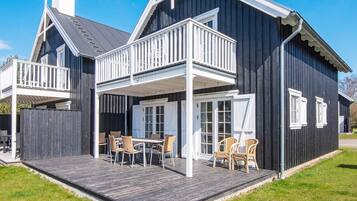 A two-story house with a balcony, a deck with outdoor furniture, and a garage.