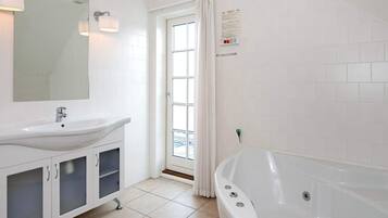 A modern bathroom with a white sink, mirror, vanity, cabinets, and a bathtub.