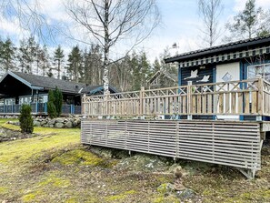 A cabin with a wooden deck, a small statue, and a building with a blue roof.