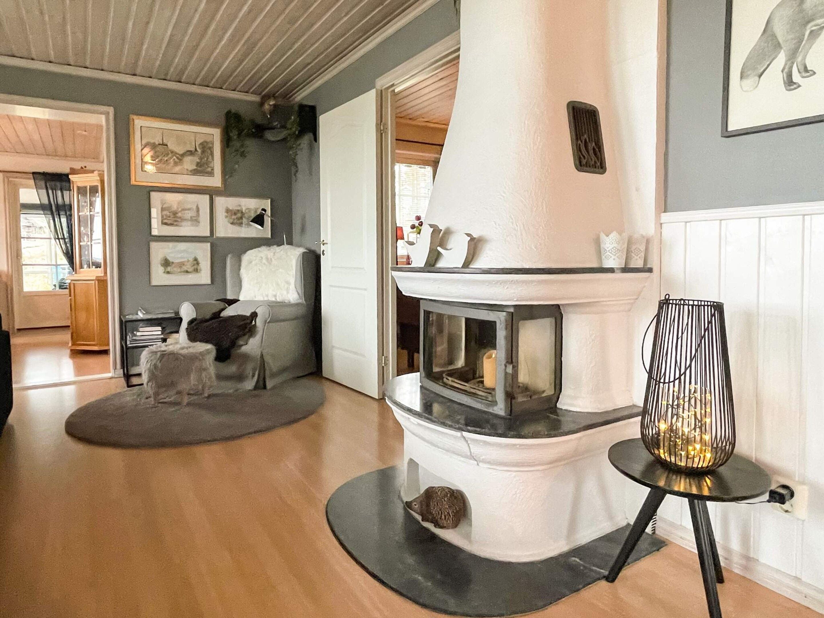 A cozy living room with a fireplace, a comfortable armchair, and a rug.