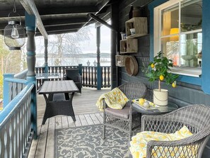 A covered outdoor seating area with wicker furniture, a table, and a potted lemon tree. - 5 Person Holiday Home in Soderkoping (Soderkoping)