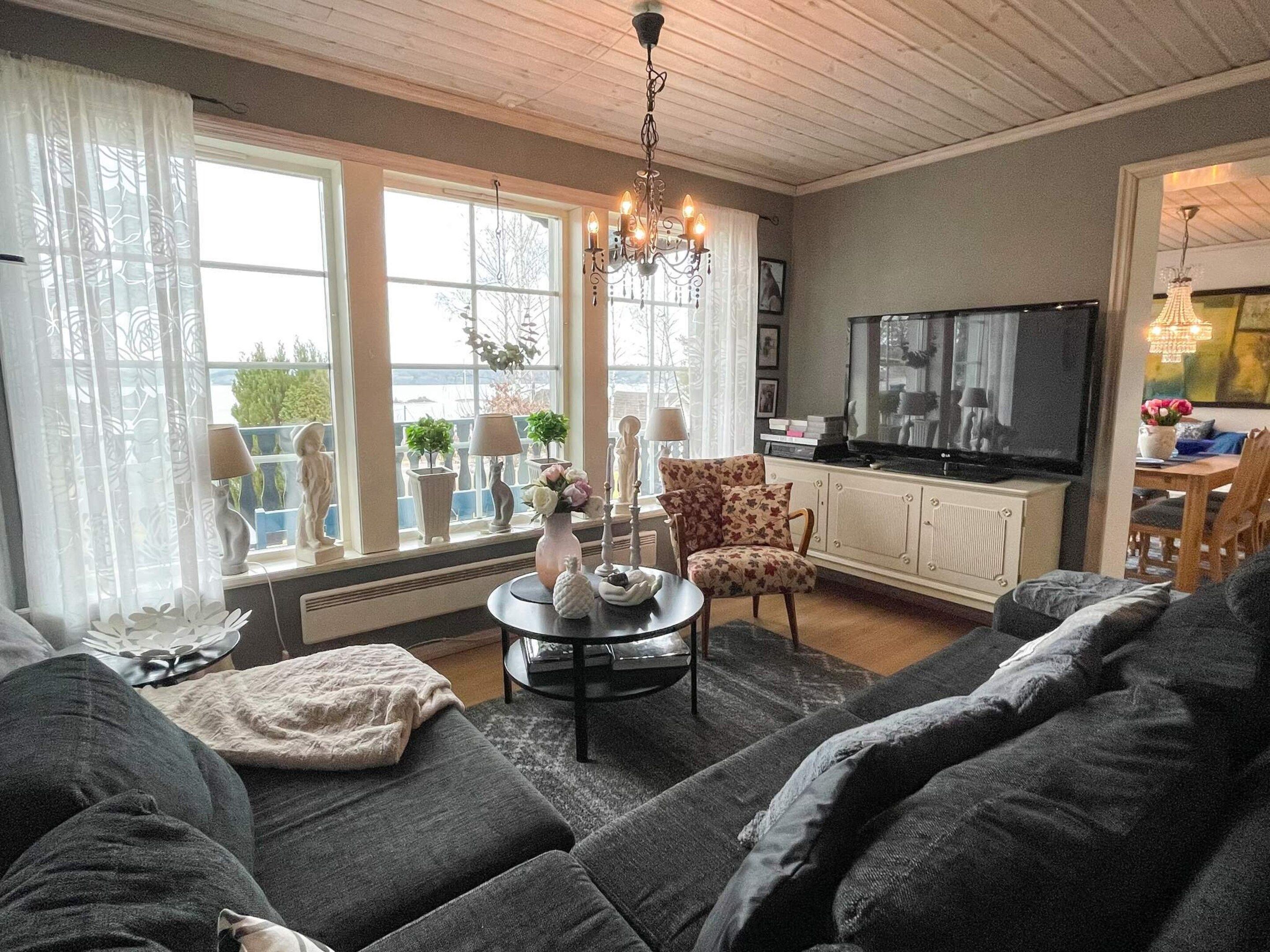 A living room with a sofa set, a coffee table, a TV, and a chandelier.