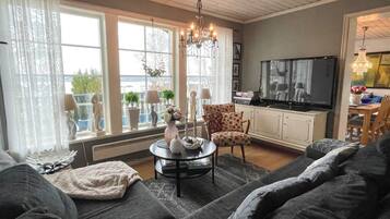 A living room with a sofa set, a coffee table, a TV, and a chandelier.