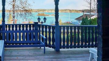 A wooden deck with a railing, overlooking a body of water and distant land.