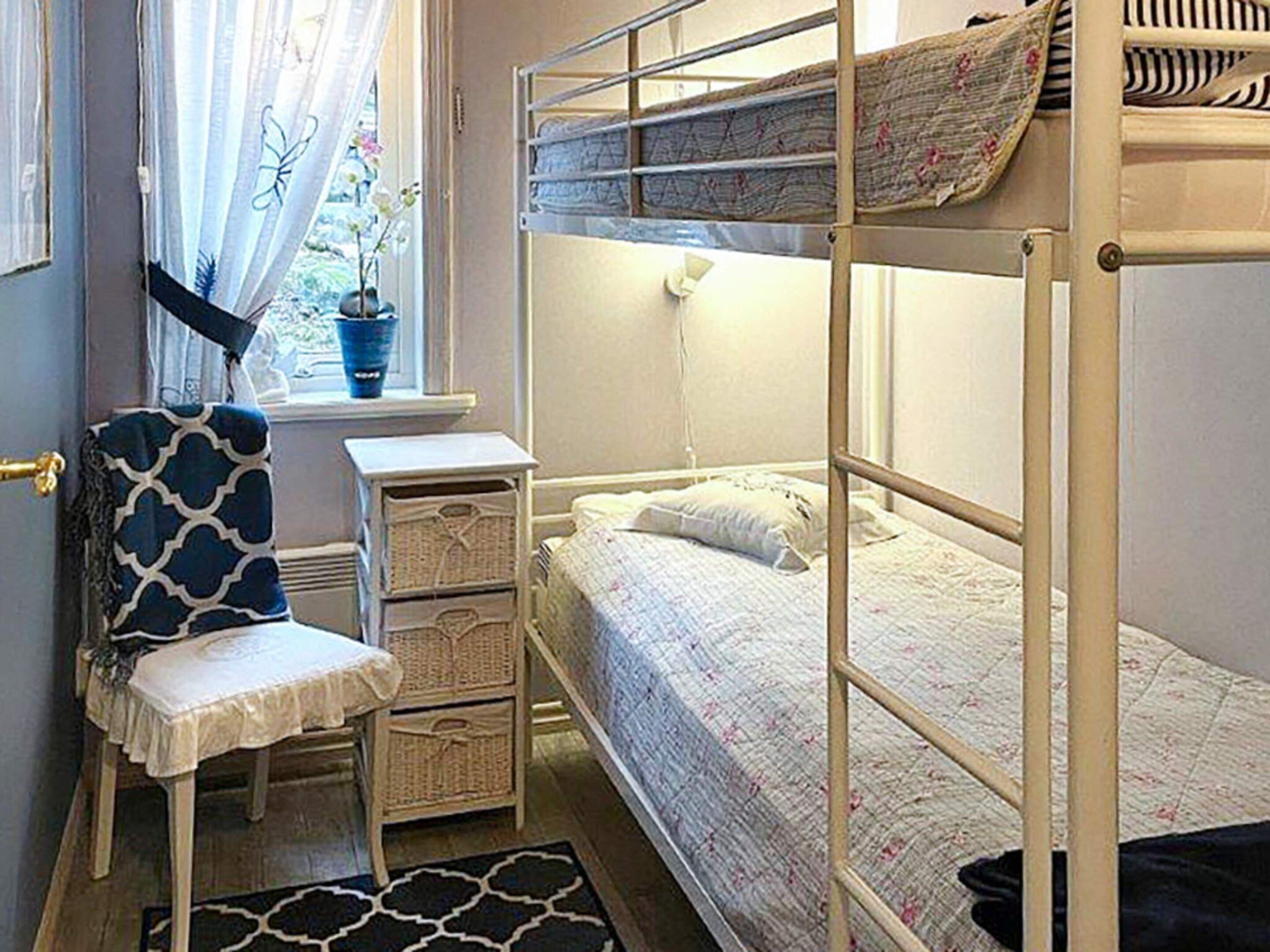 A bunk bed with a window, a desk, and a chair in a room.