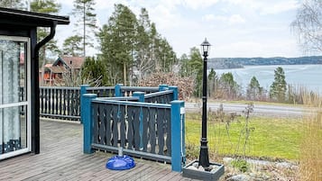 A wooden deck with a blue railing, a lamp post, and a view of a lake.