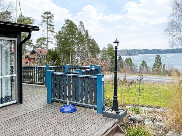 A wooden deck with a blue railing, a lamp post, and a view of a lake.