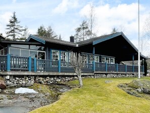 A cabin with a stone foundation, a wooden deck, and a large open porch. - 5 Person Holiday Home in Soderkoping (Soderkoping)