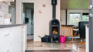 Une cuisine moderne dotée d’un poêle à bois, de meubles blancs et d’un coin repas avec une table et des chaises.