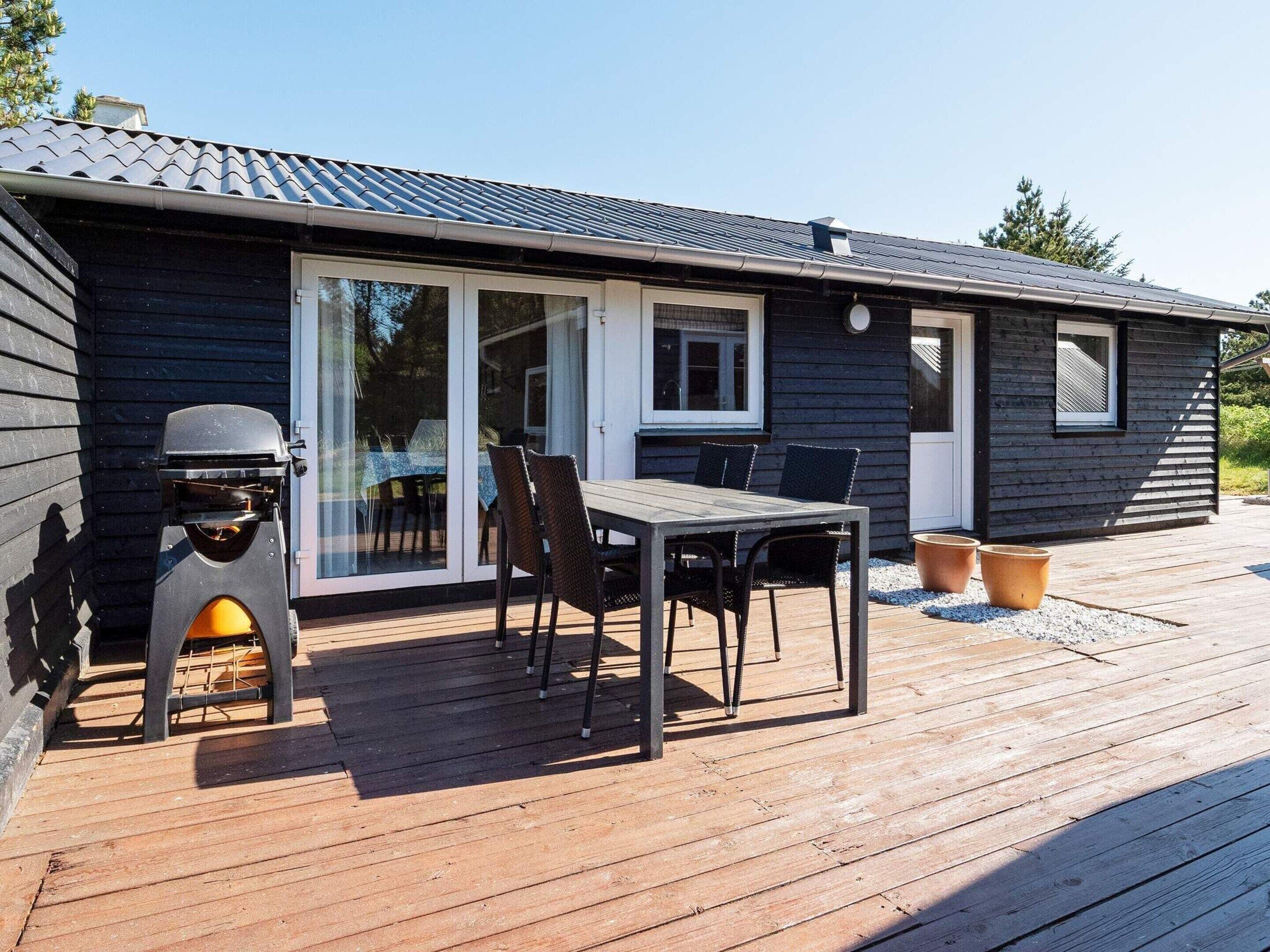 A modern outdoor dining area with a grill, a table, and chairs.