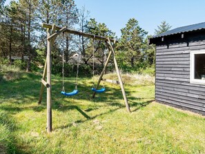 A wooden swing set in a grassy area with a small cabin. - Serene Holiday Home in Jutland near Sea (Thisted)