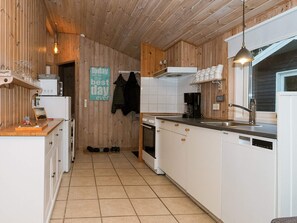 Una cocina moderna con paneles de madera, armarios blancos, una encimera negra y un colgante de techo.