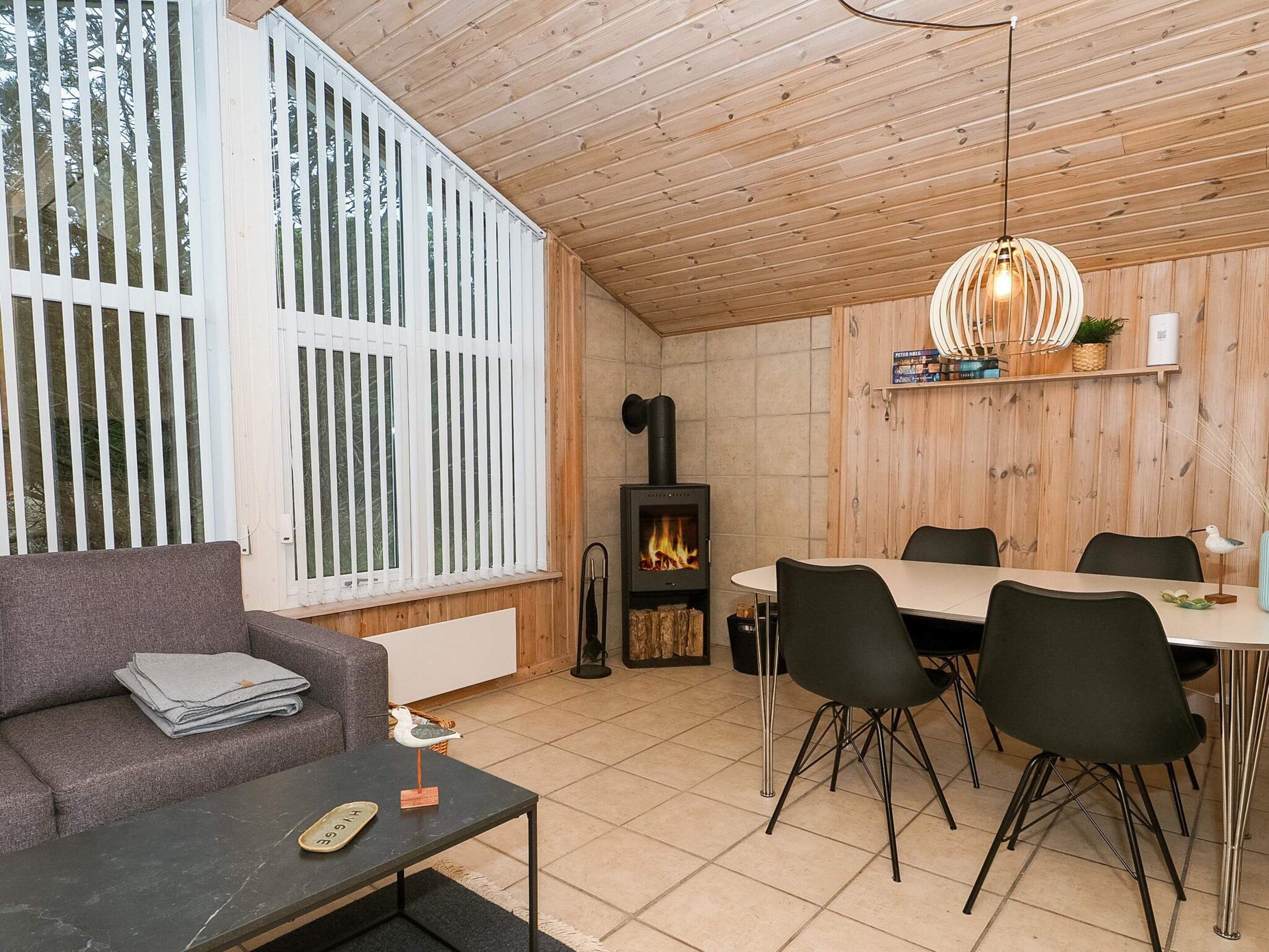 Un espacio de sala acogedor con un sofá, una mesa de comedor con sillas, una chimenea y una lámpara colgante.