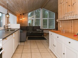 Una cocina acogedora con techo de madera, un sofá empotrado y una zona de comedor con mesa de madera.