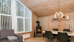 A cozy living room with a fireplace, a dining area with chairs, a sofa, and a coffee table. - Serene Holiday Home in Jutland near Sea (Thisted)