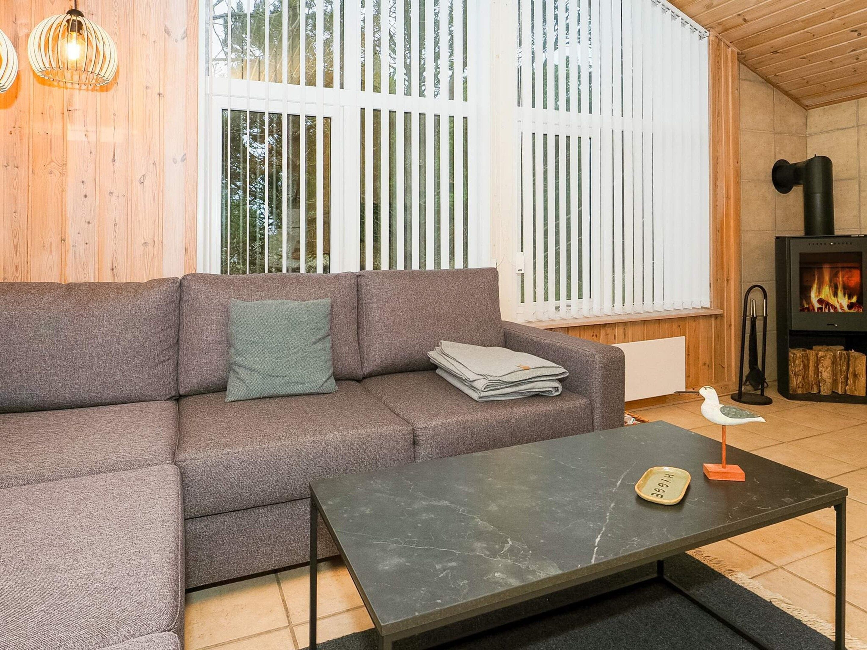 Un salon chaleureux avec un canapé gris, une table basse noire et une cheminée.